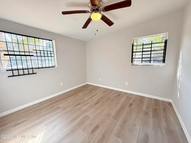 an empty room with windows and fan