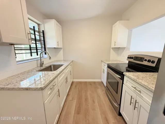 a kitchen with granite countertop a sink a counter space appliances and cabinets