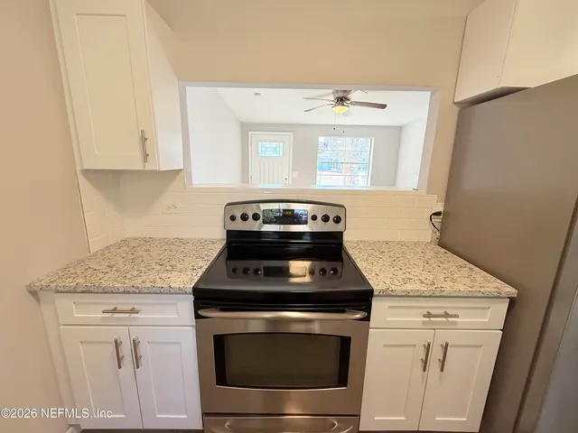 a kitchen with granite countertop white cabinets and white appliances
