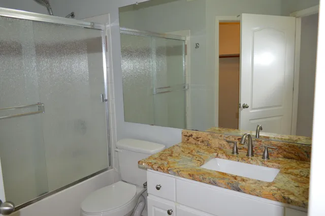 a bathroom with a granite countertop sink toilet and shower