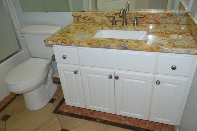 a bathroom with a granite countertop sink and a toilet