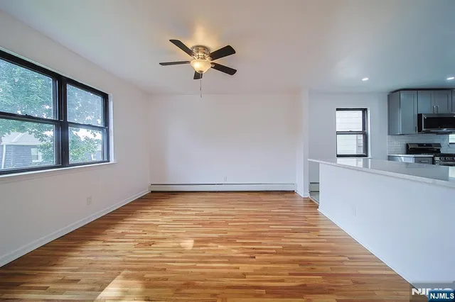 a view of an empty room with window and wooden floor