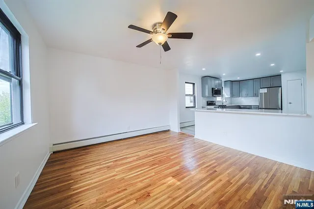 a view of empty room with wooden floor and window