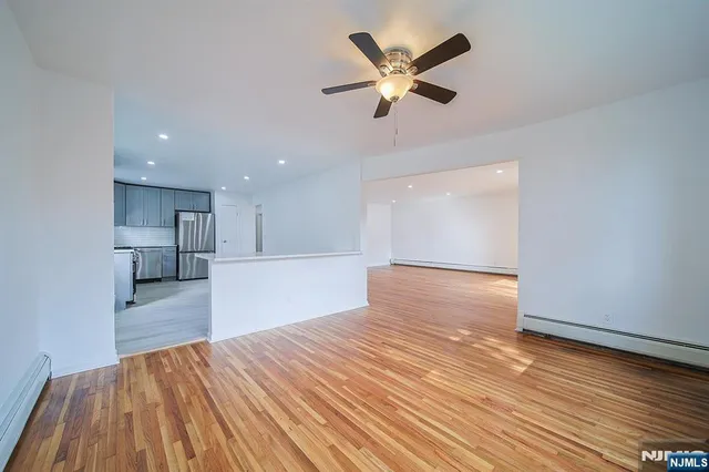 a view of a kitchen with kitchen island a sink wooden floor and a large window