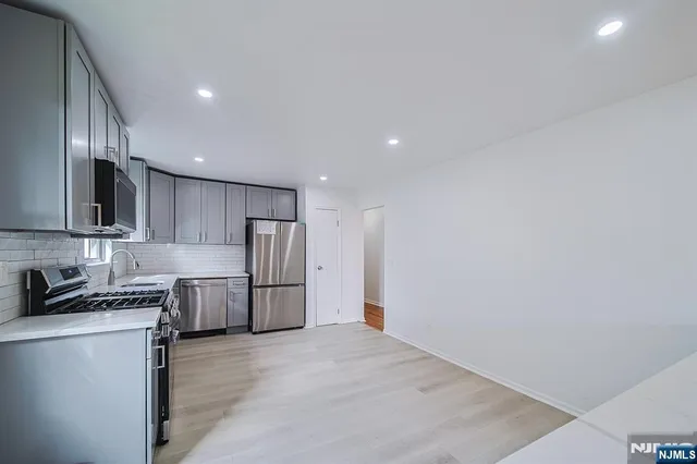 a kitchen with granite countertop a refrigerator and a stove top oven