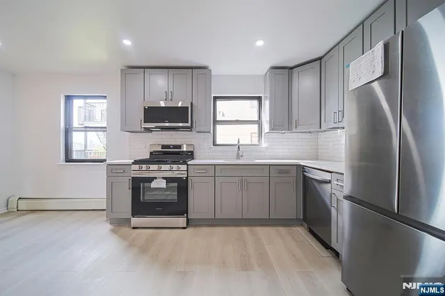a kitchen with stainless steel appliances granite countertop a stove a sink and a refrigerator