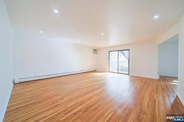 a view of an empty room with window and wooden floor