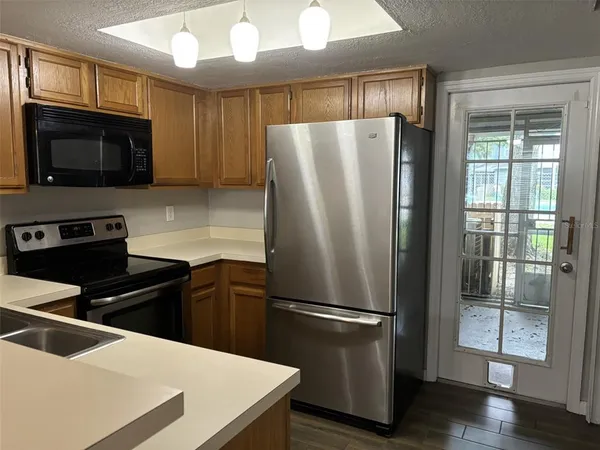 a kitchen with granite countertop a refrigerator a sink a stove a microwave and wooden floor