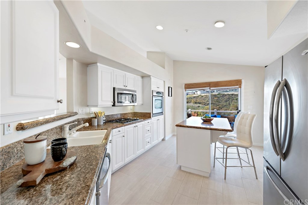 43 Cassis Dana Point, CA 92629 - Photo 6 of 41 a large white kitchen with a sink a stove a refrigerator and blue cabinets