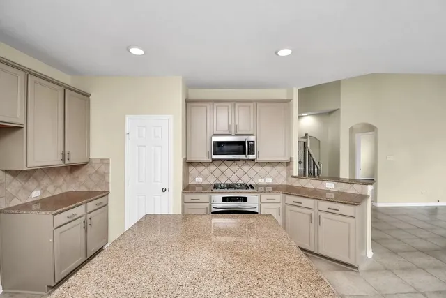 a kitchen with stainless steel appliances granite countertop a stove a sink and a refrigerator