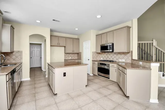 a kitchen with granite countertop a sink stove and refrigerator
