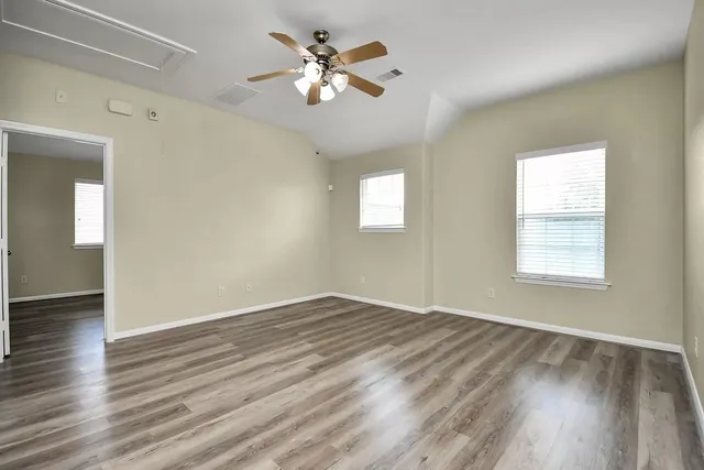 an empty room with wooden floor and windows
