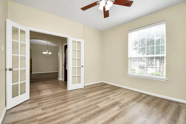 an empty room with wooden floor chandelier and windows