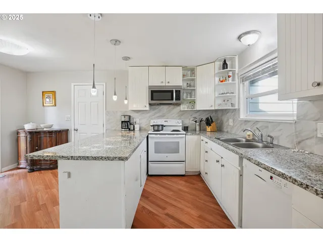 a kitchen with granite countertop a sink stainless steel appliances and white cabinets