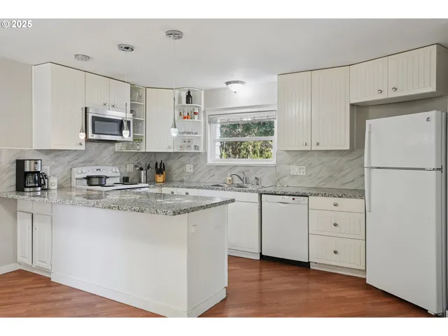 a kitchen with granite countertop white cabinets and white appliances