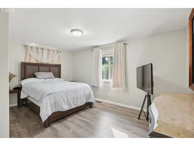 a bedroom with a bed tv and a window