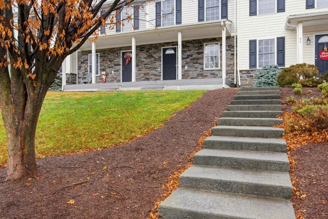 a view of a house with a yard and large tree