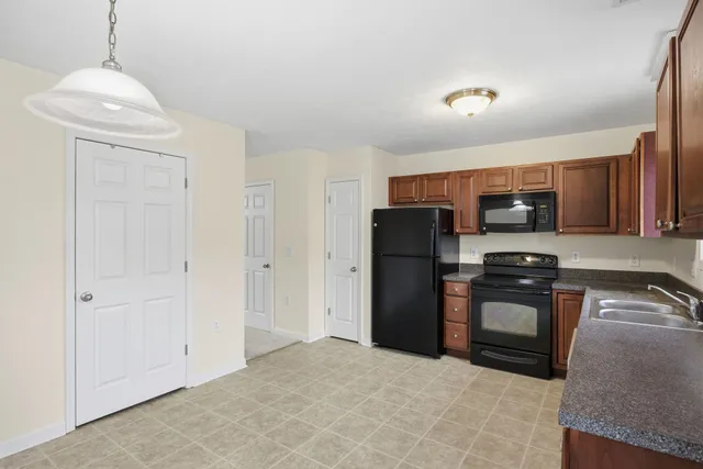 a kitchen with stainless steel appliances granite countertop a refrigerator a stove and a sink with wooden cabinets