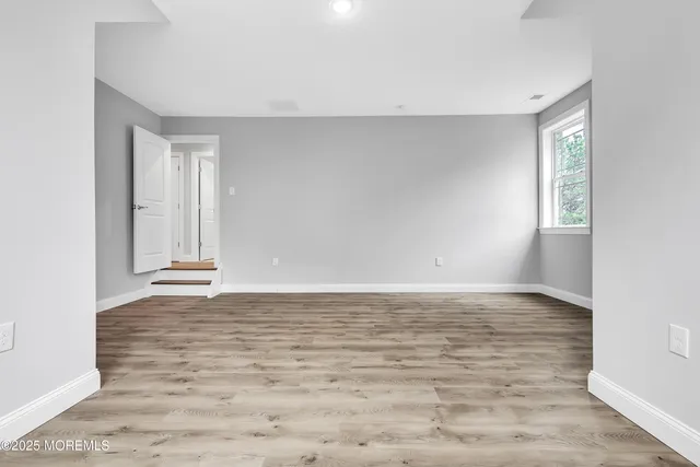 a view of an empty room with window and wooden floor