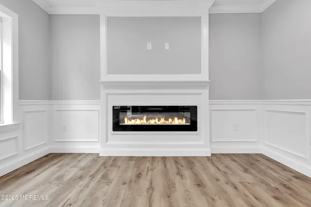 a view of an empty room with wooden floor fireplace and a window