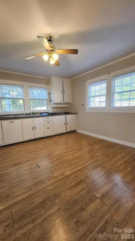 a view of a kitchen with kitchen island a sink wooden floor and a window