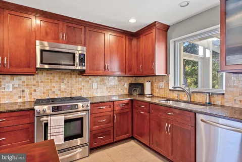 a kitchen with granite countertop wooden cabinets stainless steel appliances and a window