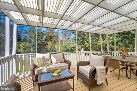 a view of a patio with couches chairs and wooden floor