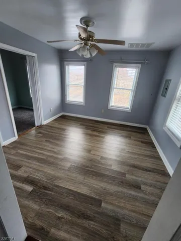 a view of empty room with wooden floor and fan