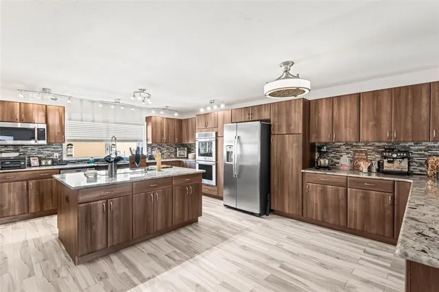 a kitchen with stainless steel appliances granite countertop a refrigerator a stove and a wooden floors