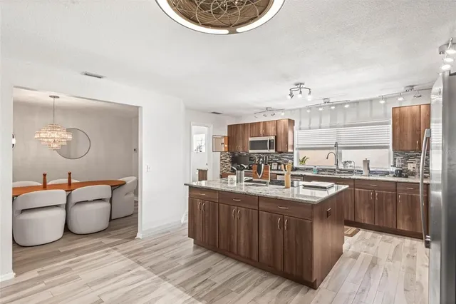 a kitchen with stainless steel appliances granite countertop a sink dishwasher a stove with wooden cabinets and floor