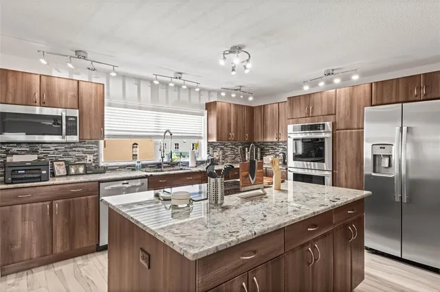 a kitchen with stainless steel appliances a sink stove microwave and refrigerator