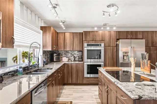 a kitchen with kitchen island granite countertop a sink a counter top space appliances and cabinets