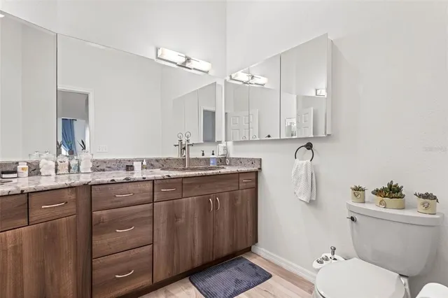 a bathroom with a granite countertop sink a toilet and a mirror
