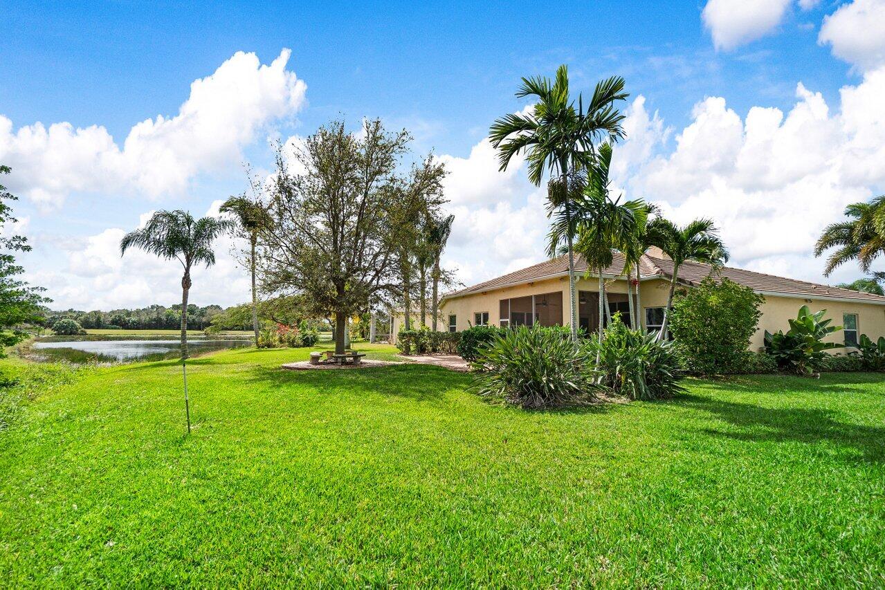 521 Southwest Lake Manatee Way Port St. Lucie, FL 34986 - Photo 31 of 33 a view of a house with a big yard and palm trees