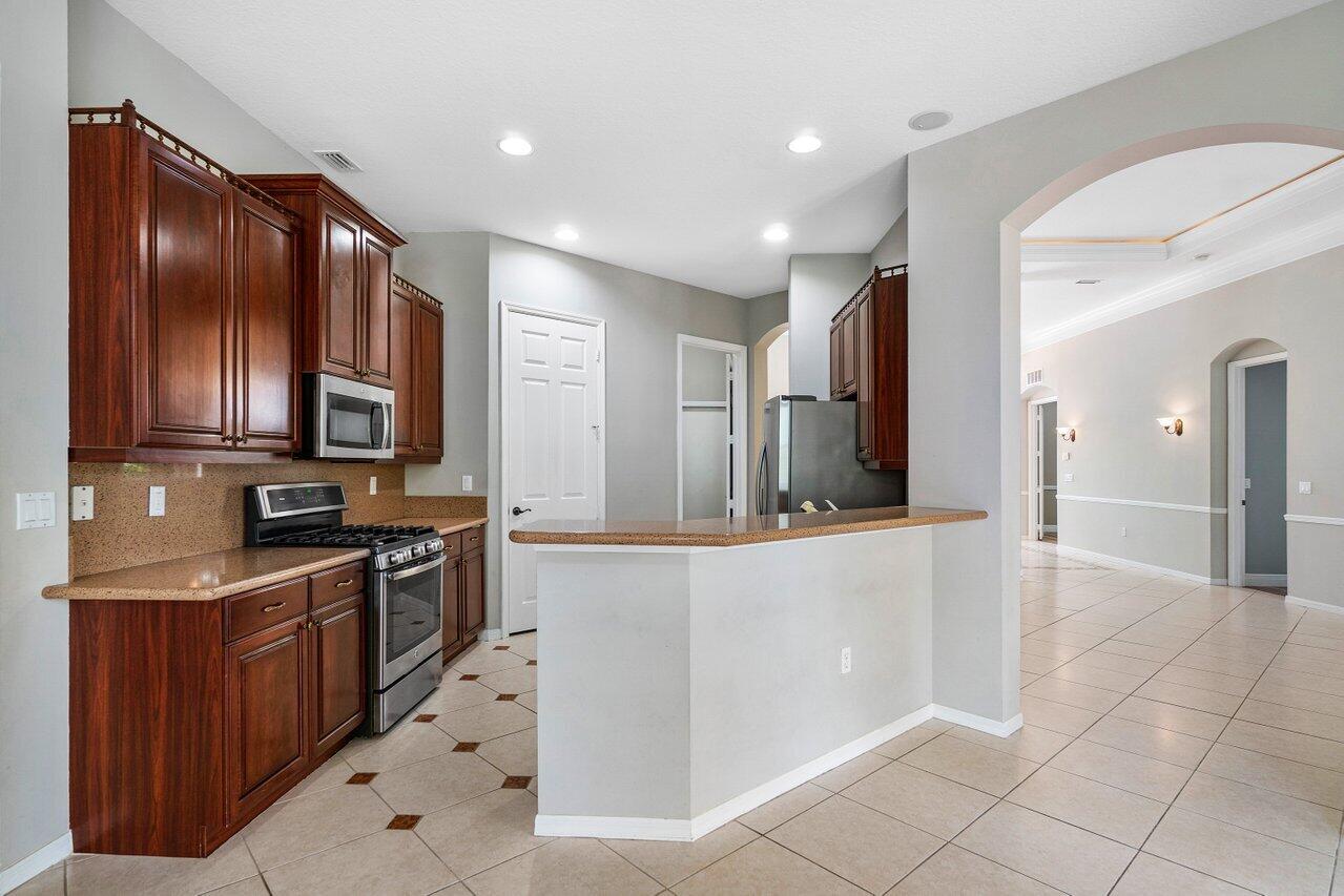 521 Southwest Lake Manatee Way Port St. Lucie, FL 34986 - Photo 5 of 33 a large kitchen with stainless steel appliances wooden cabinets and granite counter tops