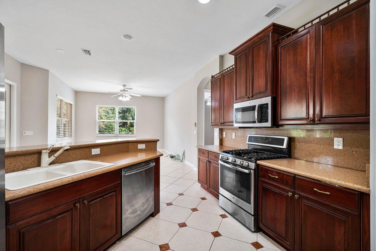 521 Southwest Lake Manatee Way Port St. Lucie, FL 34986 - Photo 6 of 33 a kitchen with stainless steel appliances granite countertop a sink stove and microwave