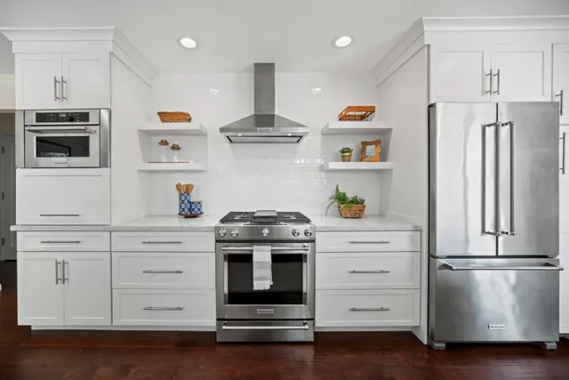 a kitchen with stainless steel appliances white cabinets and wooden floor