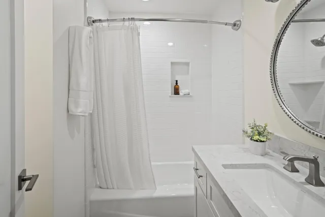 a bathroom with a sink tub vanity and a mirror