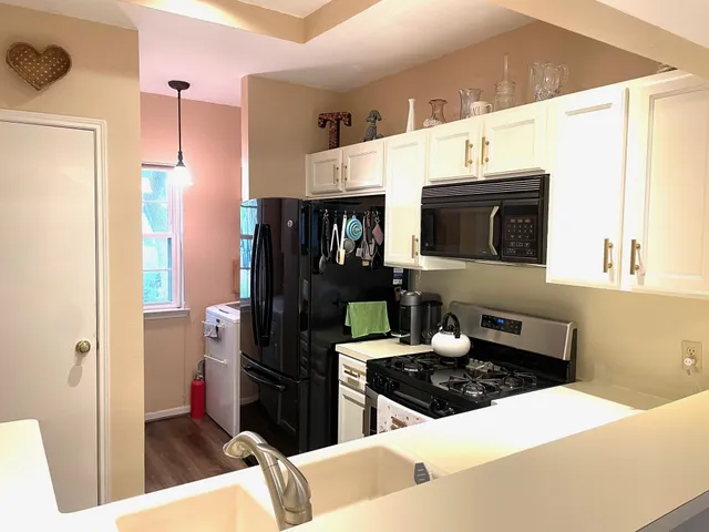 a kitchen with stainless steel appliances a stove a microwave a refrigerator a sink and white cabinets