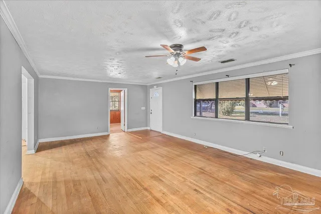 an empty room with chandelier fan and windows