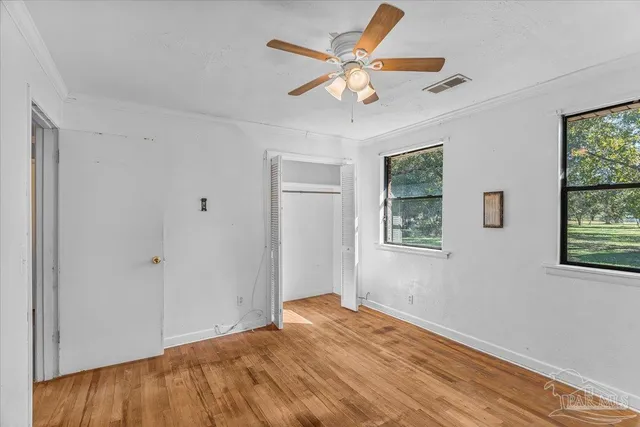 a view of empty room with wooden floor and fan