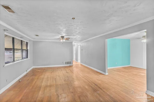 a view of an empty room with window and wooden floor