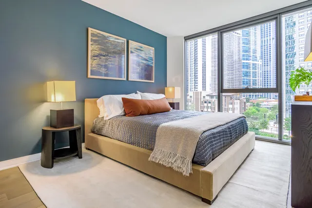 a bedroom with a bed lamp and a large window