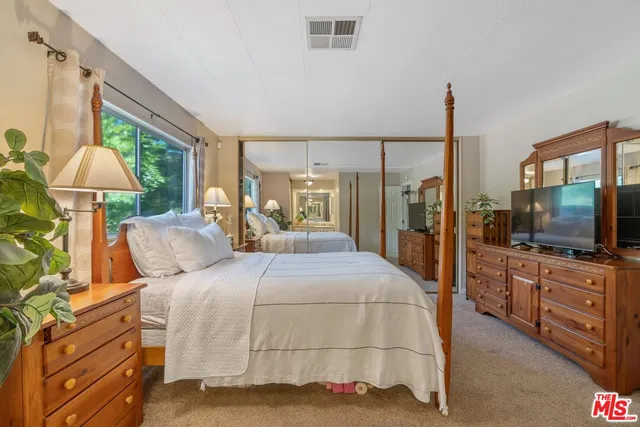 a bedroom with a large bed and a flat tv screen on dresser