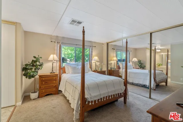 a bedroom with a bed mirror and window