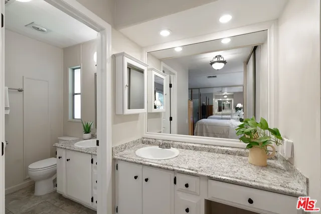 a bathroom with a granite countertop sink a toilet and a mirror