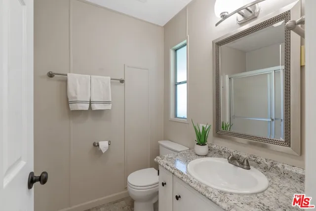 a bathroom with a granite countertop sink a toilet and mirror