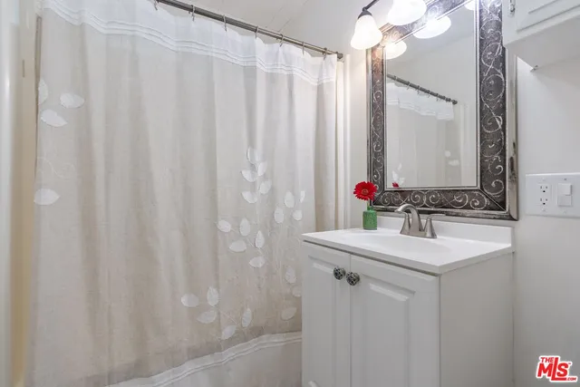 a bathroom with a sink vanity mirror and a shower