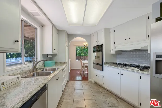 a kitchen with granite countertop a sink a counter top space and cabinets