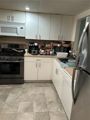 a kitchen with stainless steel appliances granite countertop a stove a sink and a white refrigerator